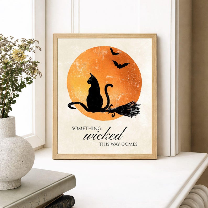 Framed black cat Halloween print beside a window with a vase of greenery, cozy fall home decor