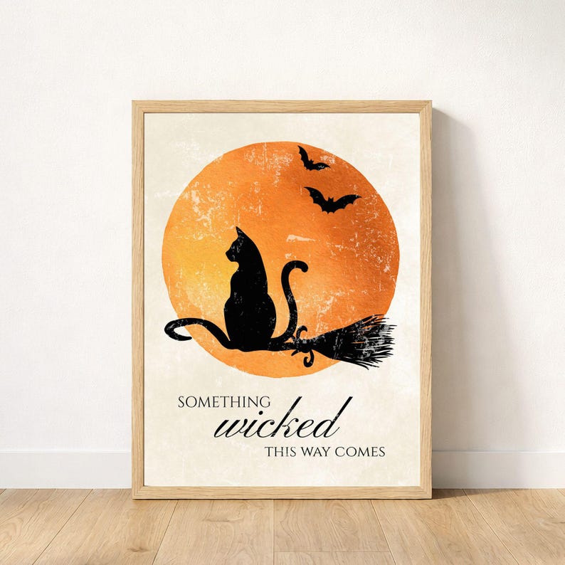 Black cat and orange moon Halloween printable in a wood frame leaning against the wall on a wood floor