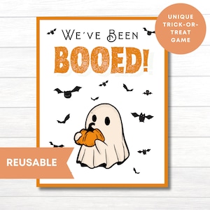 May include: A printable "We've Been Booed!" sign with a cute ghost holding a pumpkin. The sign is decorated with bats and has an orange border. It is a reusable trick-or-treat game.