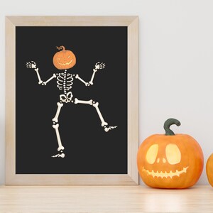 Dancing skeleton with orange pumpkin head on a black wall art print; funny Halloween digital download for farmhouse decor.
