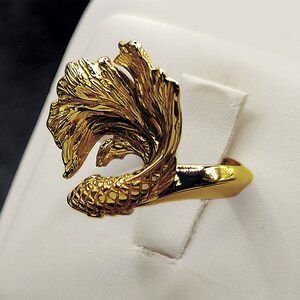 May include: A gold ring featuring a detailed design of a fish with flowing fins.