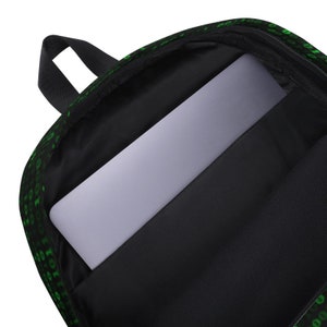 K&ouml;nnte beinhalten: Schwarzer Rucksack mit gr&uuml;nem Bin&auml;rcode-Muster. Der Rucksack hat ein Laptopfach mit einem grauen Laptop im Inneren.