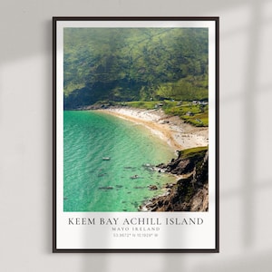 May include: A framed print featuring Keem Bay Achill Island, Mayo Ireland. The image showcases a vibrant turquoise bay with a sandy beach, surrounded by lush green hills. The print includes the location's coordinates.