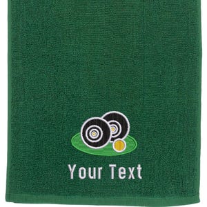 May include: Green towel with an embroidered design of three black and white bowls on a green patch of grass. The text "Your Text" is embroidered below the design.