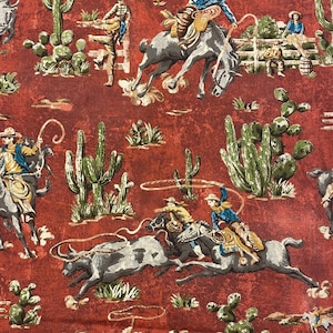 May include: A red fabric with a repeating pattern of cowboys riding horses and bulls. The cowboys are wearing blue, red, and yellow clothing. The horses and bulls are brown and white. The background is a red color with green cacti.