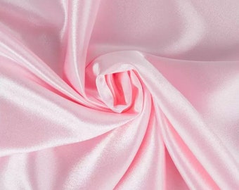 May include: A close-up of soft, pink satin fabric with a smooth, silky texture. The fabric is draped and folded, creating a luxurious and elegant look.