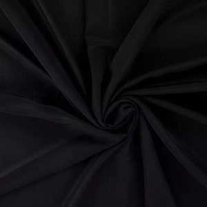 May include: Black fabric with a smooth, silky texture. The fabric is draped and folded, creating a soft, flowing look.