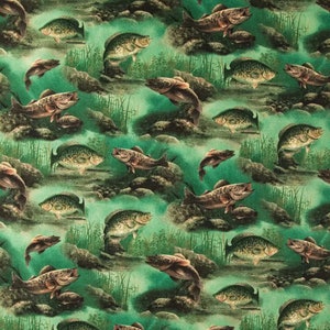 May include: A green and brown fabric with a repeating pattern of fish swimming in water. The fish are brown and have black eyes. The water is a light green color and there are brown rocks and green plants in the background.