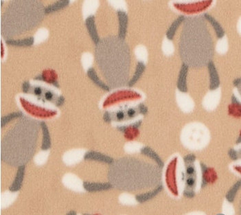 May include: Tan fabric with a repeating pattern of gray sock monkeys wearing red hats. The monkeys have white feet and are in various positions.
