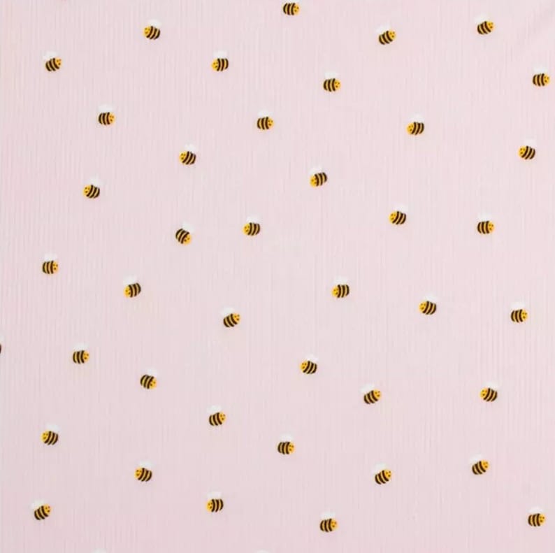 Puede incluir: Una tela rosa con un patr&oacute;n repetitivo de peque&ntilde;as abejas amarillas.