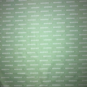 May include: A green fabric with a white repeating pattern of small triangles. The triangles are arranged in rows, with each row offset from the one above it.