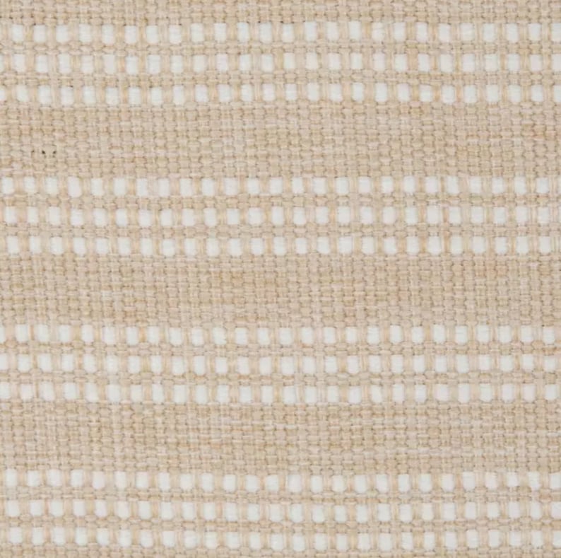 Op de afbeelding: Beige stof met een wit geweven patroon. De stof heeft een subtiele textuur en een licht ruw gevoel.