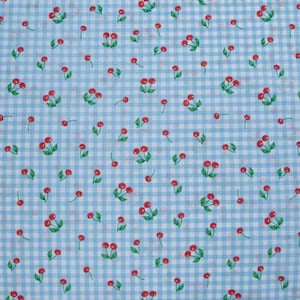 May include: A fabric with a light blue and white checkered pattern. Scattered across the fabric are red cherries with green leaves. The cherries are in clusters and single cherries are also present. The fabric has a cheerful, summery feel.
