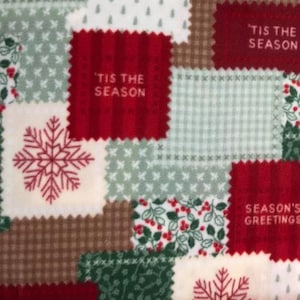 May include: A fleece fabric featuring a patchwork design with alternating squares of red, green, brown, and white. The pattern includes red snowflakes, holly berries, and text that reads 'TIS THE SEASON and SEASON'S GREETINGS in a block font.