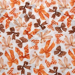 May include: A white background is covered with a pattern of various bows in shades of brown and orange. The bows have different patterns, including polka dots, stripes, and floral designs. Some bows are solid colors, while others have a gingham pattern.