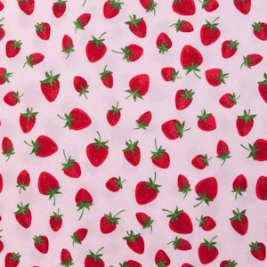 May include: A fabric with a repeating pattern of red strawberries with green stems and leaves scattered across a light pink background. The strawberries vary in size and are interspersed with small white polka dots.