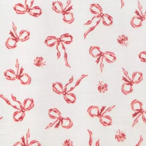 May include: White fabric with a repeating pattern of watercolor-style red bows and small roses. The bows vary in size and orientation, creating a delicate and romantic design. The fabric has a slightly textured appearance.