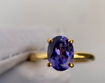 Puede incluir: Un anillo de oro con una gran piedra preciosa ovalada de color púrpura.