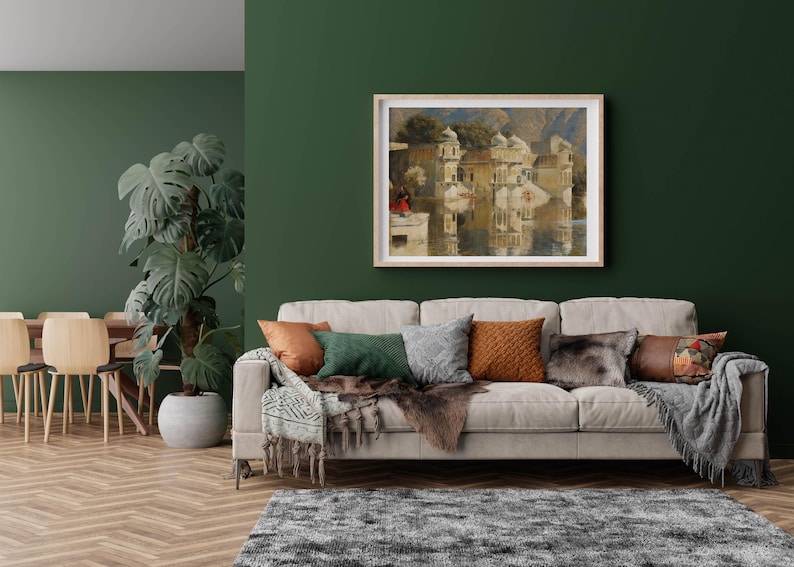 K&ouml;nnte beinhalten: Ein hellgraues Sofa mit einer Wolldecke und Kissen in einem Wohnzimmer mit einer gr&uuml;nen Wand und einem gerahmten Gem&auml;lde einer Stadtlandschaft &uuml;ber dem Sofa.