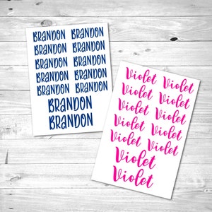 May include: Two sheets of white paper with names printed on them. The first sheet has the name "BRANDON" printed in blue, repeated 8 times. The second sheet has the name "Violet" printed in pink, repeated 9 times.