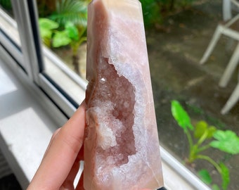 May include: A pink and white agate crystal point with a large, hollowed-out section. The crystal is polished and has a smooth, glassy surface.