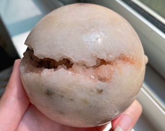 May include: A large, white, geode sphere with a crack revealing a pink and white crystal interior.