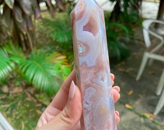 May include: A pink and white agate crystal point with a pointed tip and a smooth, polished surface. The crystal has a unique pattern of swirls and lines.