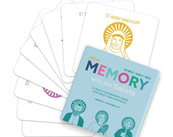 May include: A Memory with the Saints card game box in light blue with dark blue, pink, and green text. The box features illustrations of three figures with halos. Several white game cards are fanned out behind the box, each displaying a saint's name and a colored line-art illustration of a saint with a halo.