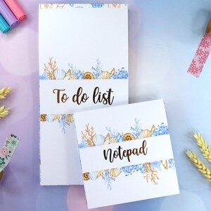 Pode incluir: Bloco de notas e lista de tarefas brancos com um design de conchas em aquarela. O design inclui conchas, corais e algas marinhas em tons de azul, bege e castanho. O bloco de notas tem a palavra "Notepad" e a lista de tarefas tem as palavras "To do list".
