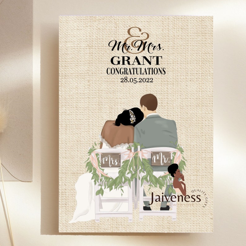 Peut inclure: Une carte de mariage avec un fond en toile de jute repr&eacute;sentant une illustration de dessin anim&eacute; d'un couple noir assis sur des chaises d&eacute;cor&eacute;es de verdure et de fleurs. Le texte sur la carte est "Mr. & Mrs. GRANT CONGRATULATIONS 28.05.2022" et "Jaiviness Quality Gifts".