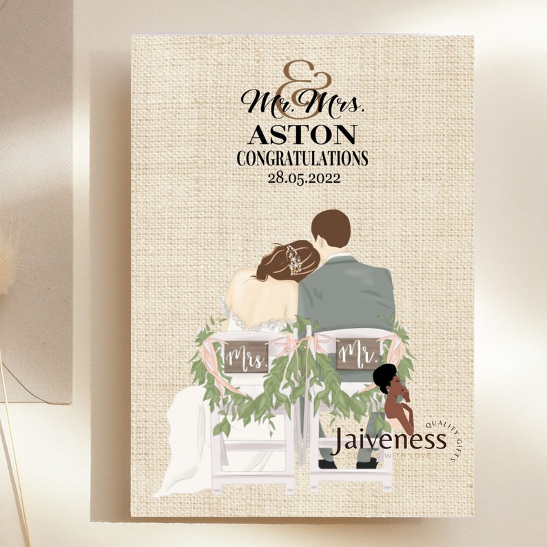 Peut inclure: Une carte de mariage avec un fond en toile de jute repr&eacute;sentant une illustration de dessin anim&eacute; d'une mari&eacute;e et d'un mari&eacute; assis sur des chaises d&eacute;cor&eacute;es de verdure et de pancartes indiquant "Mr." et "Mrs.". Le texte sur la carte est "Mr. & Mrs. Aston F&eacute;licitations 28.05.2022" et "Jaiveness Quality Gifts".