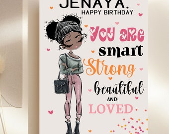 May include: A pink and white birthday card with a cartoon illustration of a young Black girl wearing a grey sweater, pink pants, and a black beanie. The card says "Jenaya, Happy Birthday. You are smart, strong, beautiful and loved." with pink hearts and confetti.