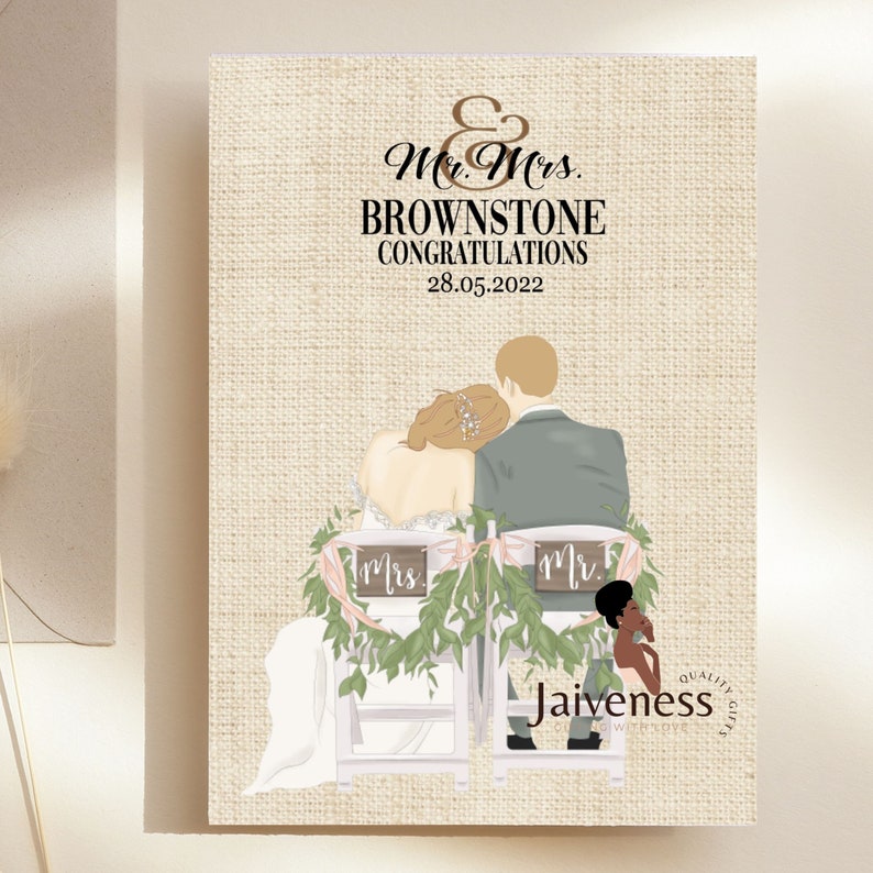 Peut inclure: Une carte de mariage avec un fond en toile de jute repr&eacute;sentant une illustration de dessin anim&eacute; d'une mari&eacute;e et d'un mari&eacute; assis sur des chaises avec de la verdure et des rubans roses. Le texte sur la carte est "Mr. & Mrs. Brownstone F&eacute;licitations 28.05.2022".