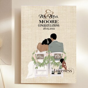 Peut inclure: Une carte de mariage avec un fond en toile de jute repr&eacute;sentant une illustration de dessin anim&eacute; d'un couple noir assis sur des chaises avec de la verdure et des pancartes indiquant "Mr." et "Mrs.". Le texte sur la carte est "Mr. & Mrs. MOORE CONGRATULATIONS 28.05.2022" et "Jaivness Quality Gifts".