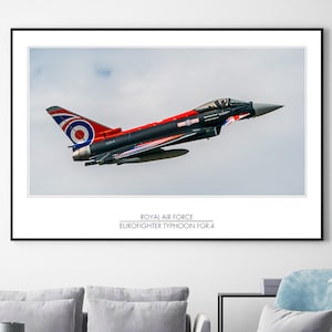 May include: A framed print of a Royal Air Force Eurofighter Typhoon FGR.4 jet in flight. The aircraft is primarily black and red with a Union Jack design on the wing. The print includes the text "Royal Air Force Eurofighter Typhoon FGR.4".