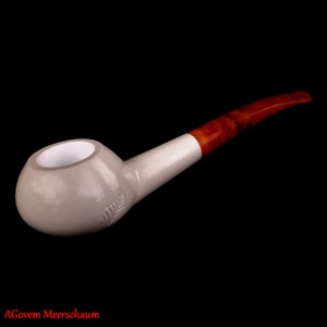 Puede incluir: Una pipa de espuma de mar blanca con una boquilla marrón. La pipa tiene una cazoleta redonda y una boquilla larga y curva.