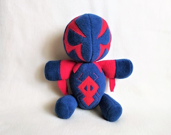 Puede incluir: Juguete de peluche azul y rojo con una cara estilizada y un símbolo rojo en el pecho.