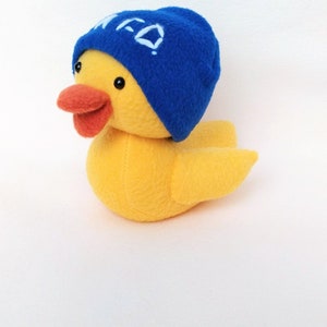 May include: A yellow plush duck wearing a blue beanie with white embroidered letters that say "MFD".