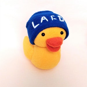 May include: A yellow plush duck wearing a blue hat with the word "LARD" embroidered in white.