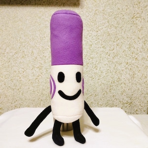 Pode incluir: Um brinquedo de pelúcia roxo e branco em forma de marcador com um rosto sorridente. O brinquedo tem braços e pernas pretos.