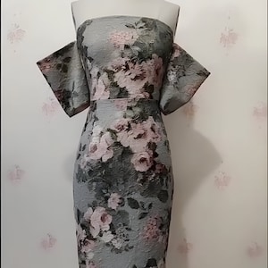 May include: A gray off-the-shoulder dress with a floral print. The dress has a fitted bodice and a flowing skirt.