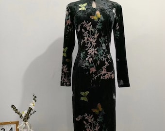 May include: A black velvet dress with a floral and butterfly print. The dress has a mandarin collar and long sleeves.