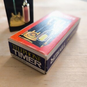 May include: A red and blue box with the words "Telephone Timer" printed on it. The box features a picture of a vintage rotary phone.