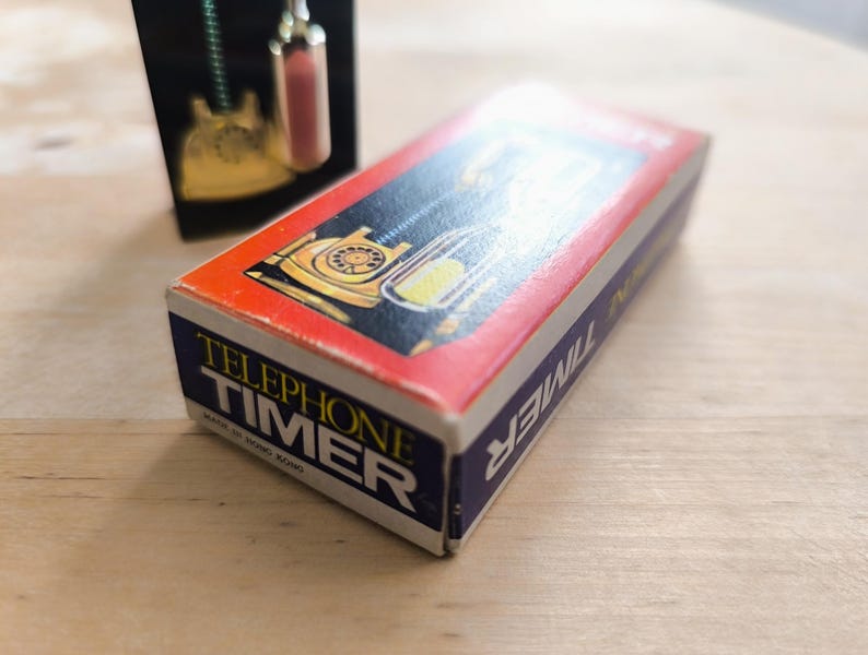 May include: A red and blue box with the words "Telephone Timer" printed on it. The box features a picture of a vintage rotary phone.
