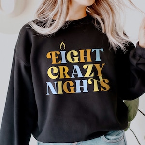 May include: Black sweatshirt with a graphic print of the text "EIGHT CRAZY NIGHTS" in yellow, blue, and orange.