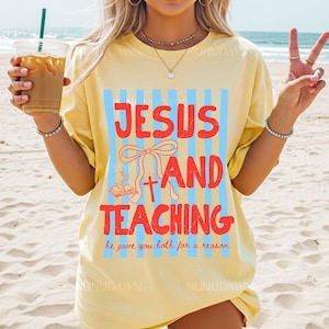 Op de afbeelding: Lichtgeel T-shirt met de tekst "JESUS AND TEACHING" in het rood, tegen blauwe verticale strepen. Het ontwerp bevat een kruis, een strik en een open boek. De zin "he gave you both for a reason" staat eronder gedrukt.