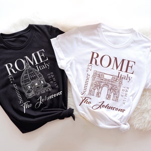May include: Two black and white t-shirts with a graphic design of Roman landmarks. The text on the shirts reads "ROME Summer '23 Italy Family Trip The Johnsons".