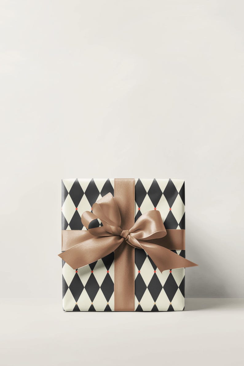May include: A wrapped gift box with a brown satin ribbon and bow. The wrapping paper has a black and white diamond pattern with small red accents. The gift is presented on a white background.