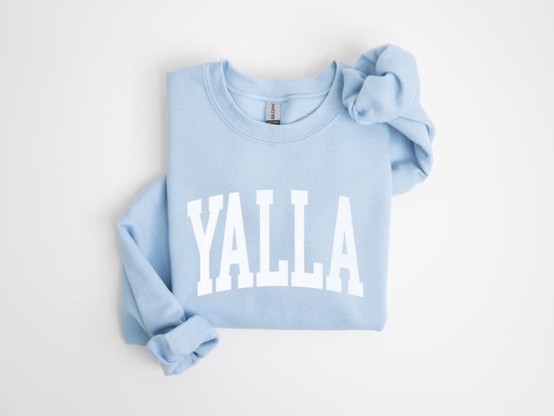 May include: A light blue sweatshirt with the word "YALLA" printed in white on the front.