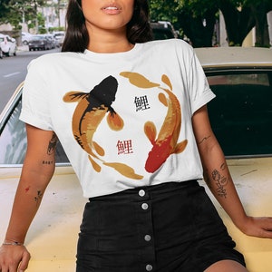 May include: White t-shirt with a graphic of two koi fish swimming in a circle. The fish are black and orange with gold accents. The word "鯉" is written in red on the shirt.